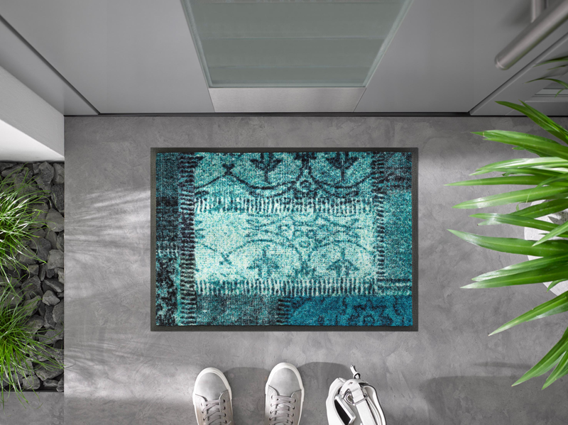 Fußmatte mit türkisen Farbflächen vor der Eingangstür