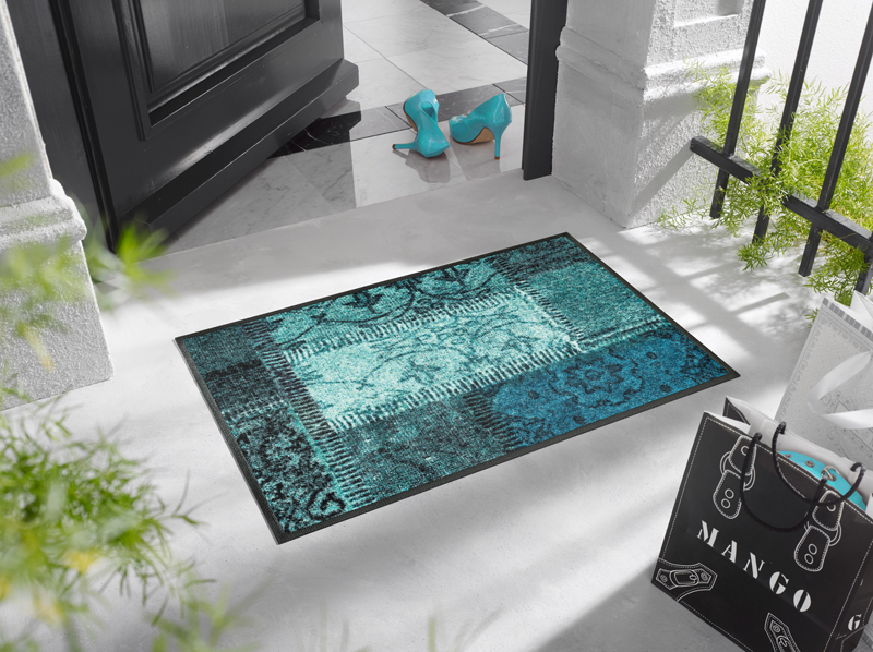 Fußmatte mit türkisen Farbflächen vor der Eingangstür